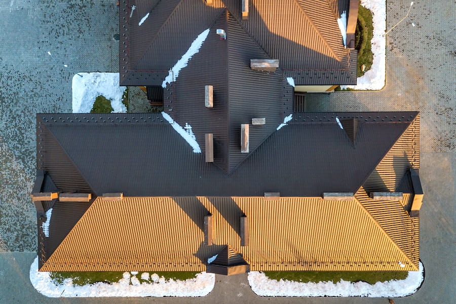 Top aerial view of building brown shingle tiled roof with complex configuration construction
