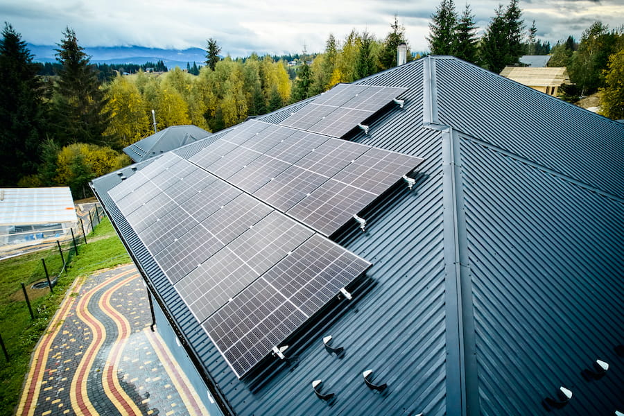 Aerial view of new modern house cottage with solar photovoltaic panel system on roof.
