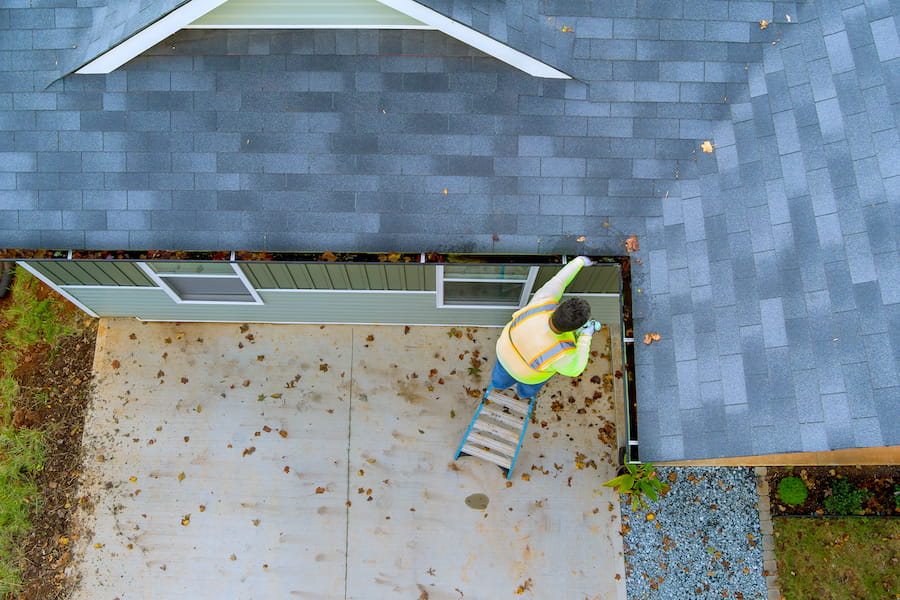 Professional roofing contractor inspecting asphalt shingles for damage